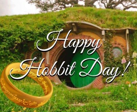 Image of the Hobbit house with a ring in the left corner of the image and the words Happy Hobbit Day written in white cursive in the center.