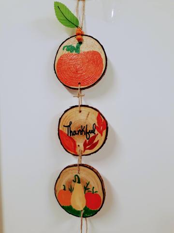 Image of the craft. Mini wooden circles hanging vertically with fall decoration.