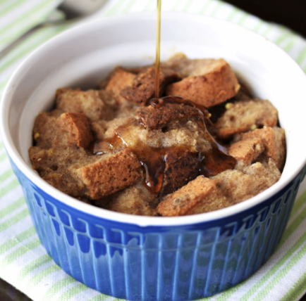 French toast casserole in a blue dish, with syrup being drizzled on it.