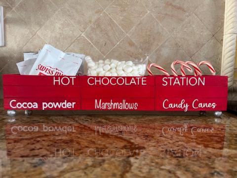 Image of the craft featuring a wooden caddy painted red with different labeled compartments for hot chocolate supplies. 