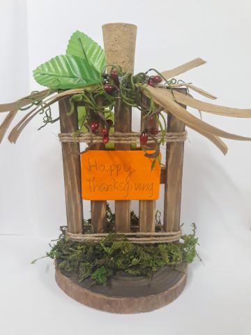 Image of the craft featuring a rustic centerpiece with wood twigs, silk leaves and a Happy Thanksgiving sign.