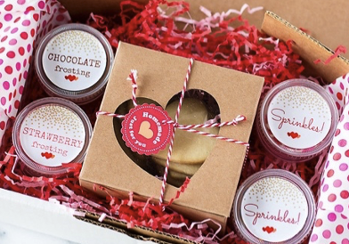 Small cookie kits resting in pink tissue papers in a cardboard box