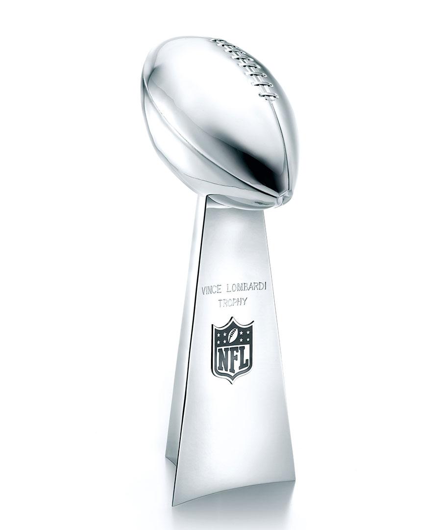 Image of the Lombardi Trophy. Silver football on a silver base.