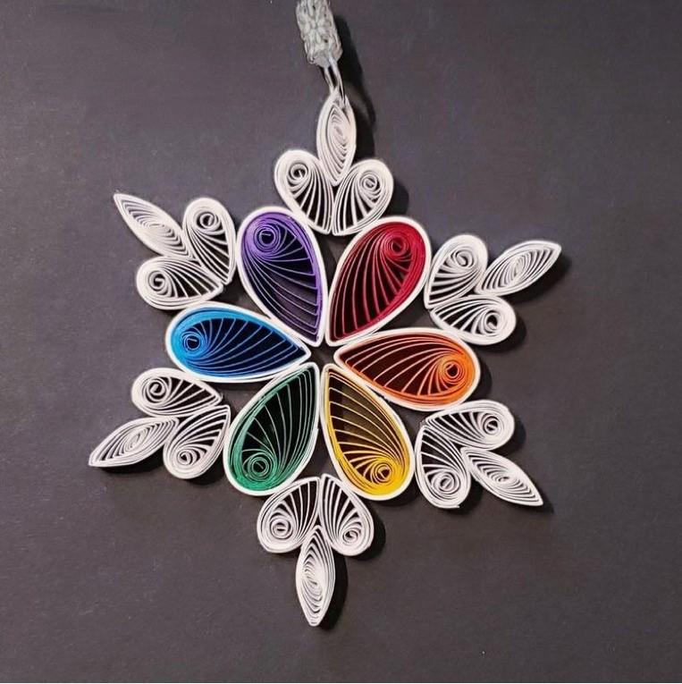 Image of the craft featuring a quilled pendant. Rolled paper put together to look like a snowflake pendant.