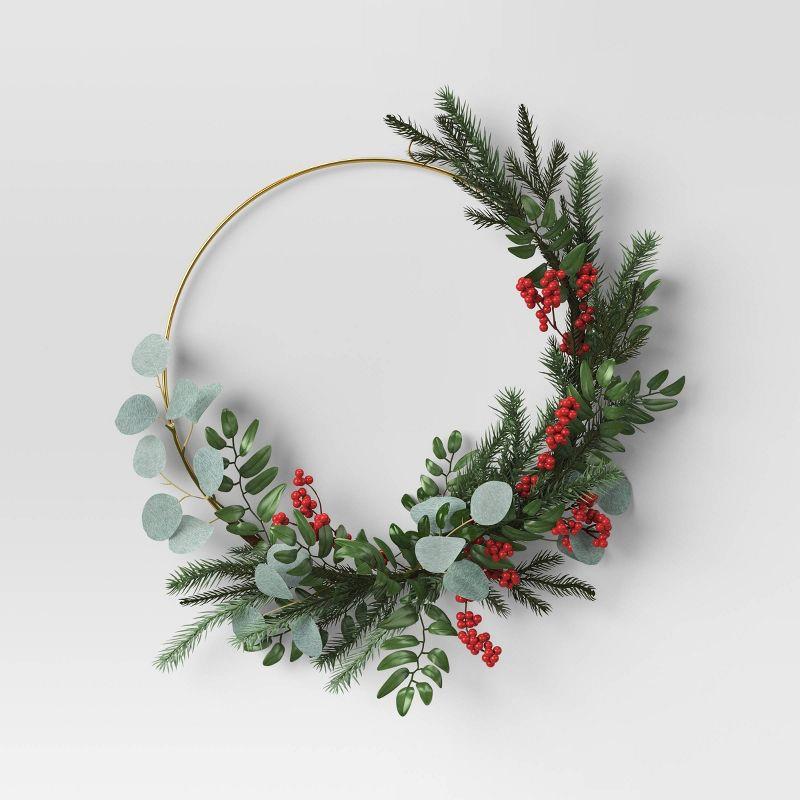 Image of the craft featuring a thin metal circle wreath decorated with pine branches and red berries.