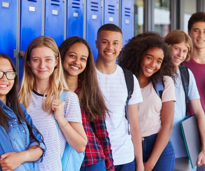 Teens standing a row in front of blue lockers